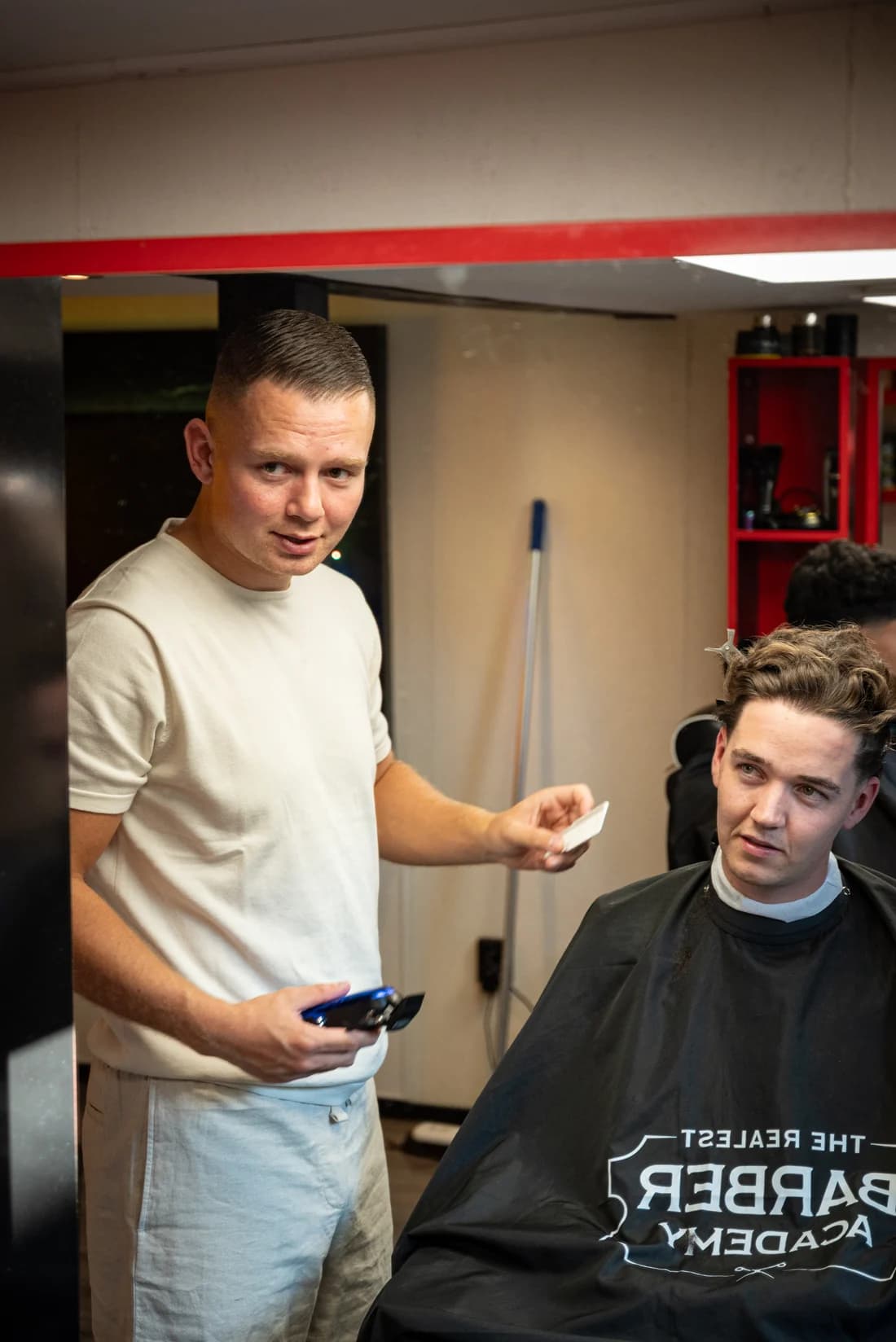 Vincent met een klant in de studio, met kam en tondeuse in de hand